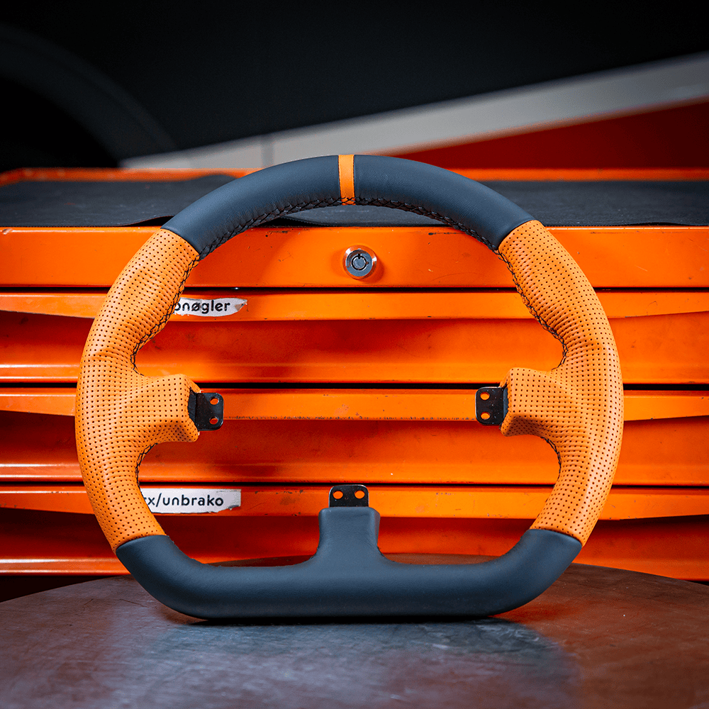 Asetek SimSports Wheel GT Rim with closed D-shape, orange leather grip and center stripe, designed for racing sim racing setups.