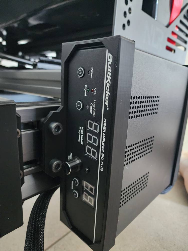 SimSportGadget Buttkicker Gamer Plus Pro amplifier power brick holder bracket mounted on wall for secure setup.