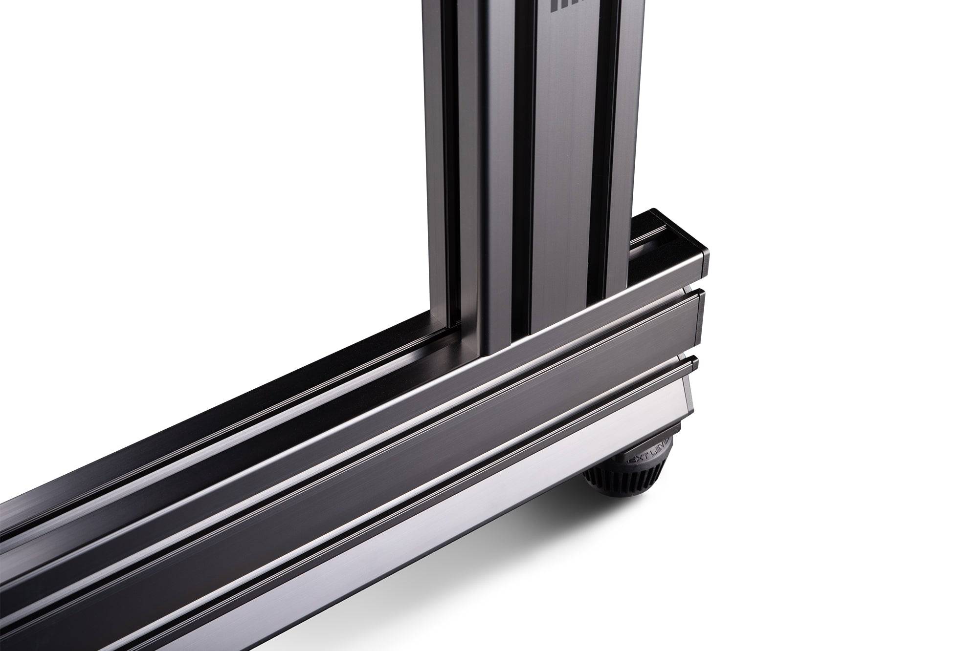 Next Level Racing Elite freestanding monitor stand in carbon grey holding a single computer monitor on a desk.